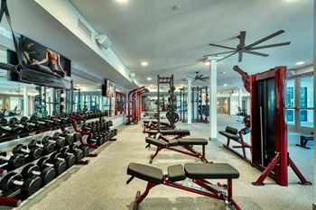 a spacious fitness center with cardio equipment and weights